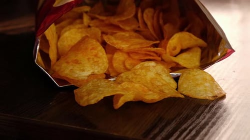 Hand Reaching into Bag of Potato Chips