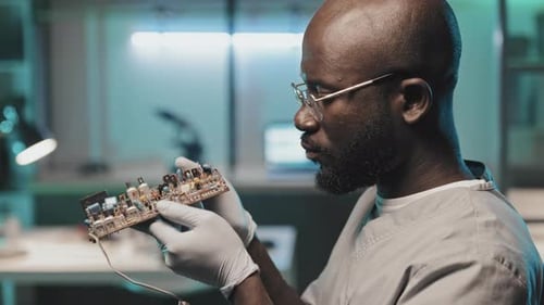 Black Technical Engineer Checking Circuit Board in Lab