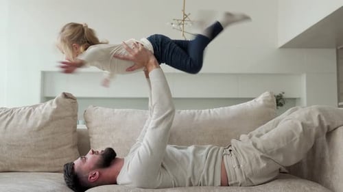 Father Lifts Daughter Up on the Sofa