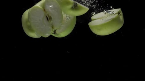 Slow Motion Apple Halves Falling Into Transparent Water on Black Background