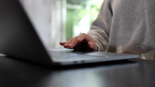 Nahaufnahme einer Frau, die am Laptop-Computer-Touchpad auf dem Tisch arbeitet und berührt