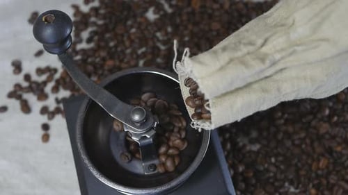 Pouring Coffee Beans into a Manual Coffee Grinder