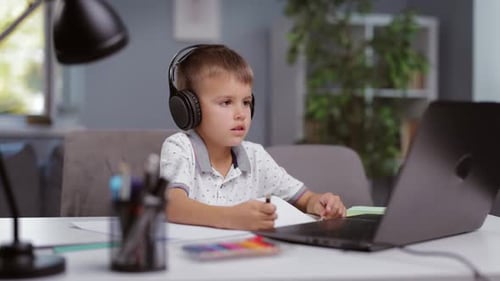 Young Boy Studies Using a Laptop and Headphones