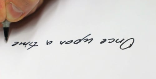 Hand Writes 'Once Upon a Time' on White Paper