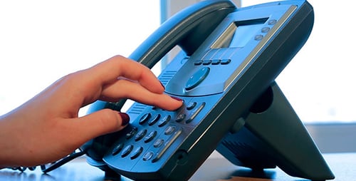 Hand Dials Phone on Gray Landline in Office