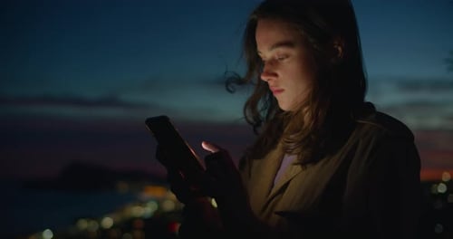 Young Woman Using Smartphone at Night in City