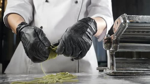Chef Arranging Fresh Green Pasta by Machine