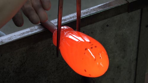 Glassblower Shapes Molten Glass with Metal Tools Close Up