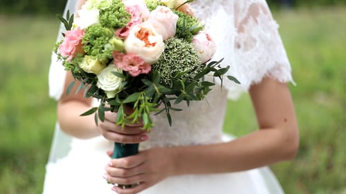 Bride Holding Wedding Bouquet with Groom Nearby