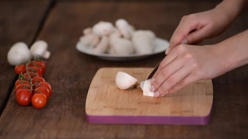 Hands Slicing Fresh Mushrooms on Cutting Board
