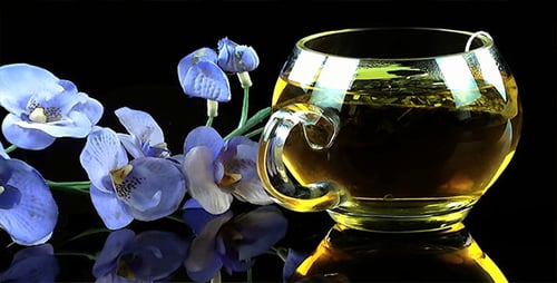 Teacup with Golden Tea and Blue Orchid Flowers