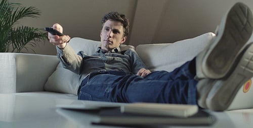 Young Adult Relaxing on Couch with Remote