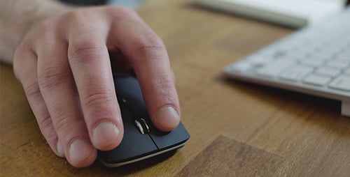 Hand Clicking Computer Mouse on Wood Desk