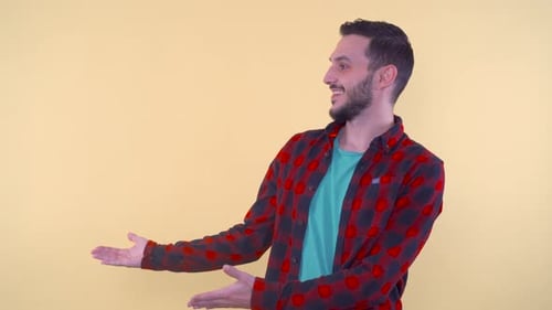 Young Adult Man Presenting on Yellow Background