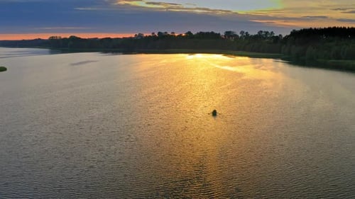 Aerial view of lonely boat on lake at sunset