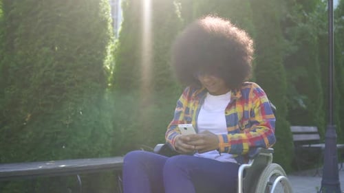 Adult with Curly Hair Using Phone in Wheelchair