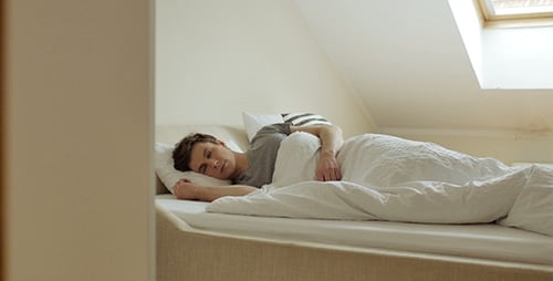 Young Man Sleeping Peacefully in Bed at Home