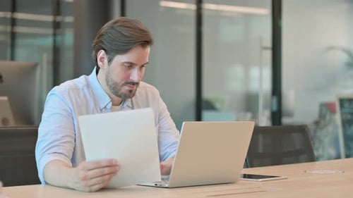 Young Adult Works at Office Table With Laptop