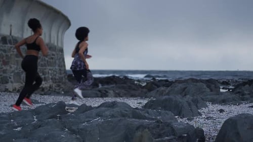 Two mixed race women running on beach