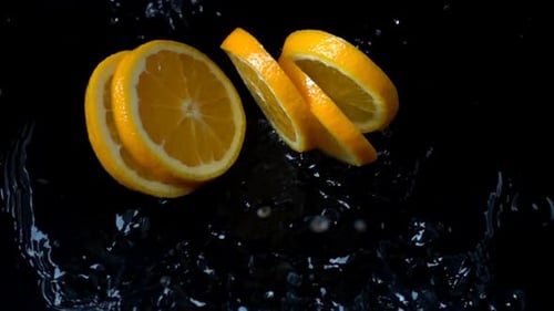 Bright Orange Slices Falling into Water with Splash