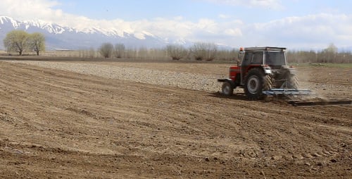 Red Tractor Tilling Field on Sunny Day