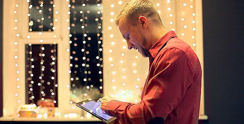 Man Using Tablet Near Holiday Lights At Night