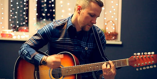 Man Playing an Acoustic Guitar on a Beautiful Back