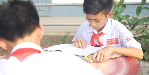Diligent Student Reading Book at School Table