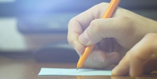Hand Writes Note on Paper in Office Setting