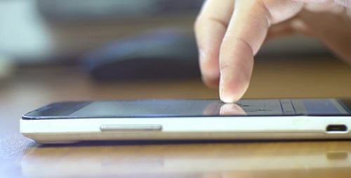 Hand Interacting with Smartphone on Desk Close Up