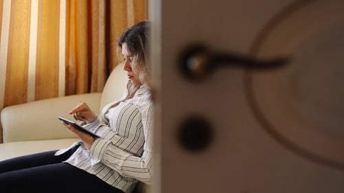 Woman Using Tablet on Couch in Bright Room