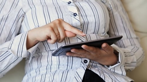 Woman Uses Tablet Device Indoors in Close Up