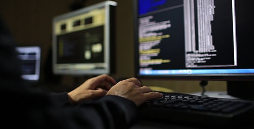 Person Coding on Keyboard in Dark Room