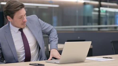 Businessman Working on Laptop in Modern Office