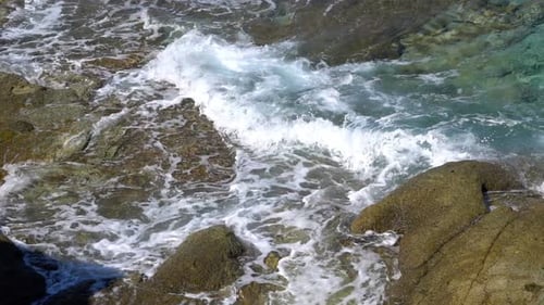 Waves Crashing on Rocky Shoreline on Sunny Day