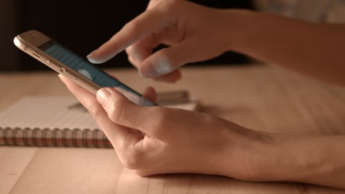 Phone Use on Desk With Notepad and Pen