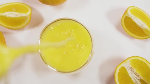 Pouring Orange Juice into Glass with Fresh Oranges