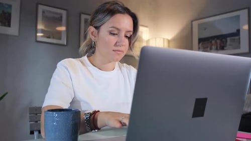 Woman working on laptop computer in home office.