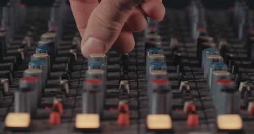 Sound engineer working in a recording studio with a sound console and microphones