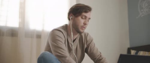 Young Adult Using Laptop Indoors with Headphones