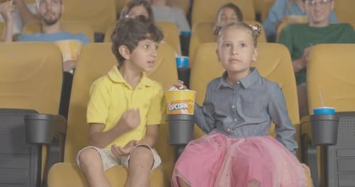 Absorbed Children Watching Film in Cinema and Eating Popcorn. Portrait of Carefree Middle Eastern