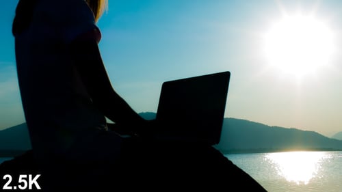 Silhouette Working on Laptop by the Water