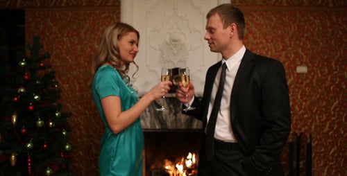Couple Toasting Champagne by Fireplace at Christmas
