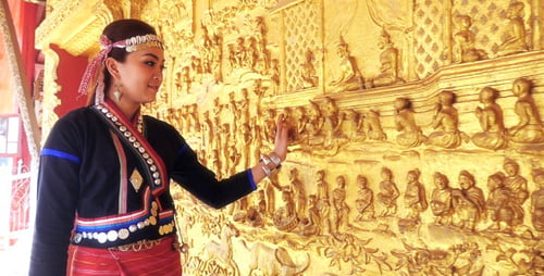 Chica con ropa tradicional tocando la pared del templo