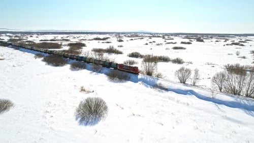 Freight Train Travels Through Snowy Winter Landscape by Drone