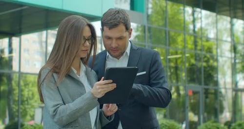 Business People Standing Near Business Center with Digital Tablet. Man and Woman Read News on Tablet