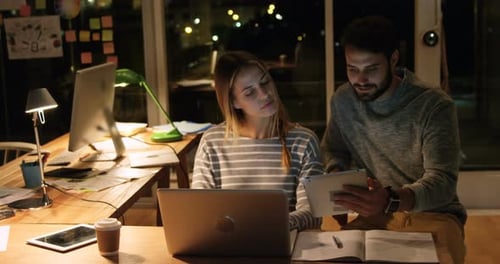 Young Adults Collaborating on Tablet in Office at Night
