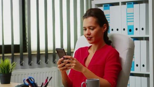 Woman Using Mobile Phone at Desk in Office