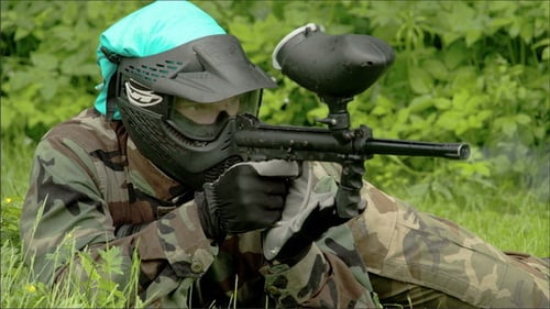 Mann liegt auf dem Boden und spielt Paintball