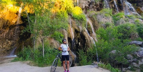 Woman Biker at Waterfall in Scenic Landscape